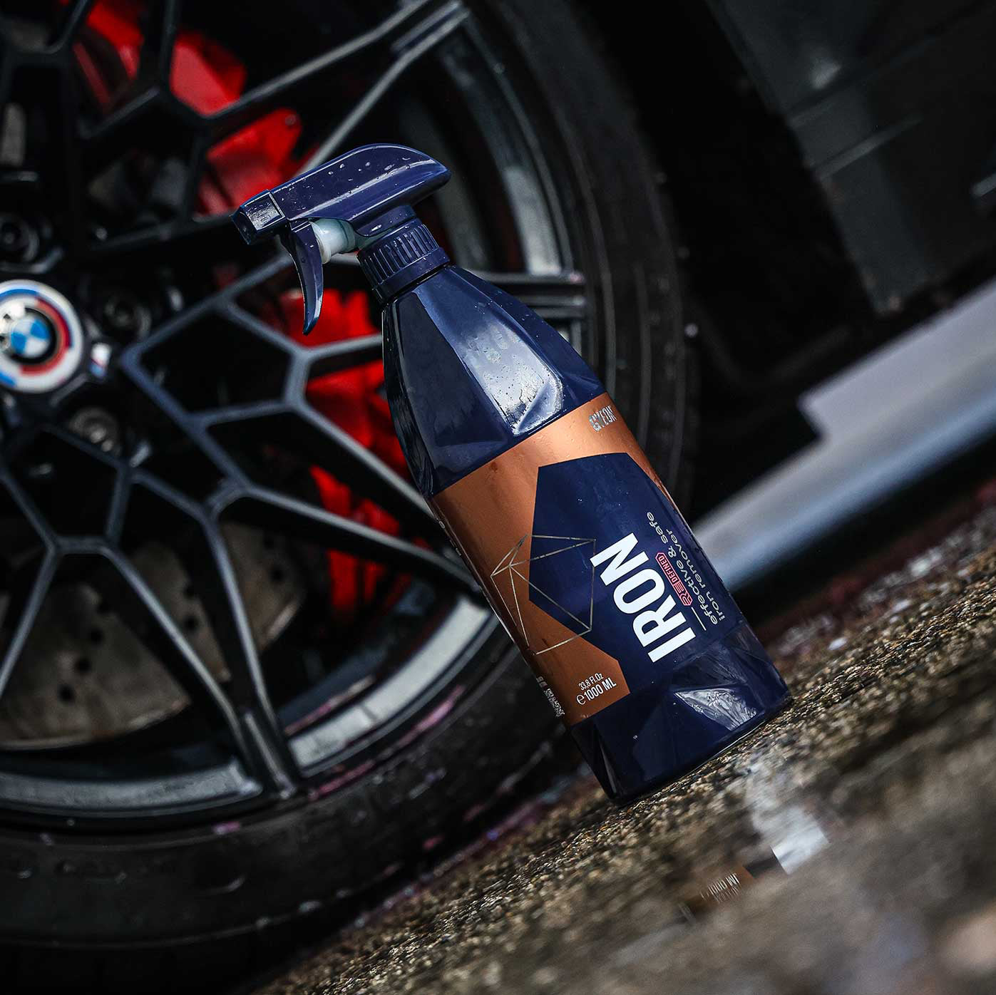 Spray bottle labeled 'IRON' on a car wheel with a BMW logo.