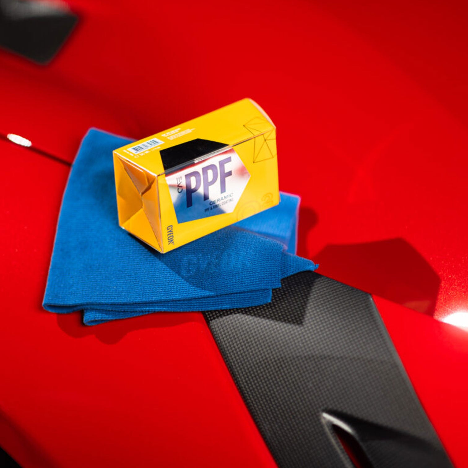 Gyeon PPF Ceramic Coating box on a blue towel with a red car surface in the background