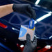 Person holding a blue bottle and white box labeled 'PURE' in front of a car interior.