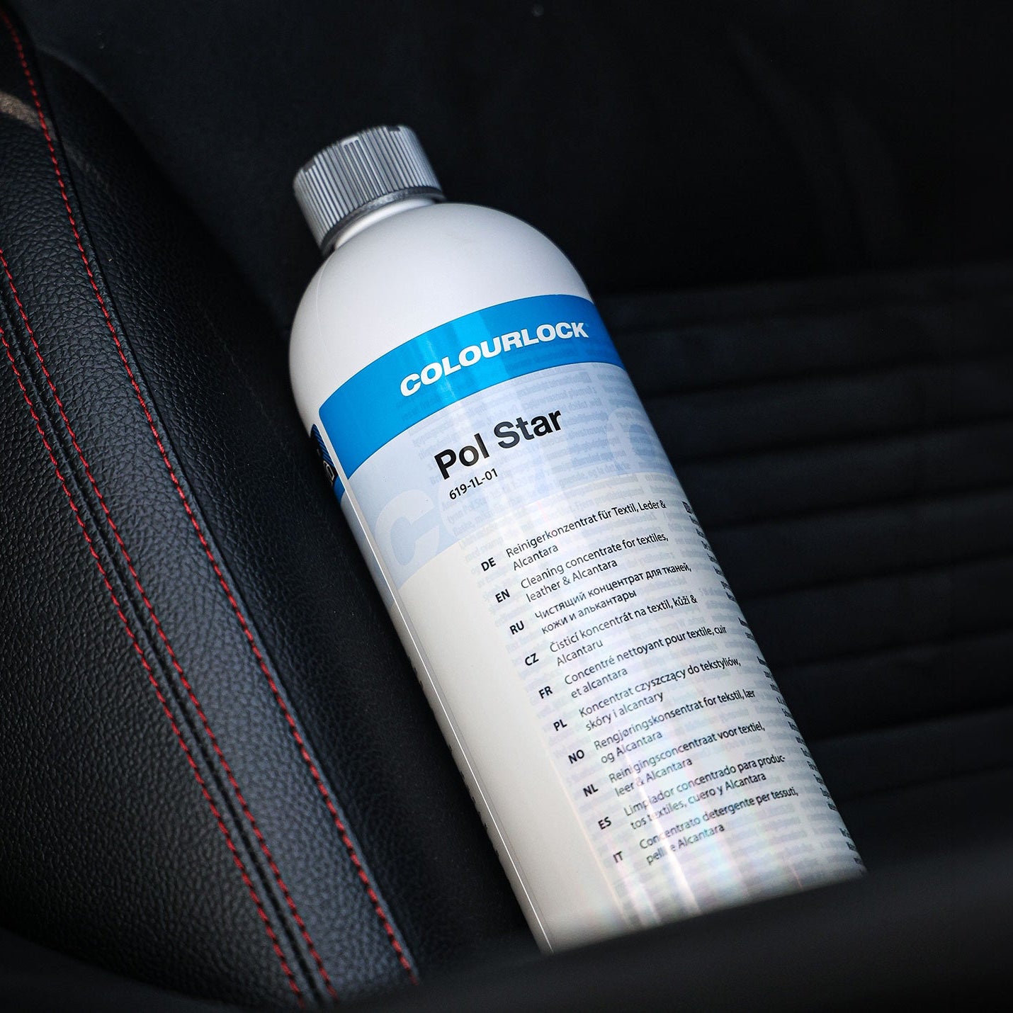 A bottle of Colourlock Pol Star car polish resting on a black leather car seat with red stitching.