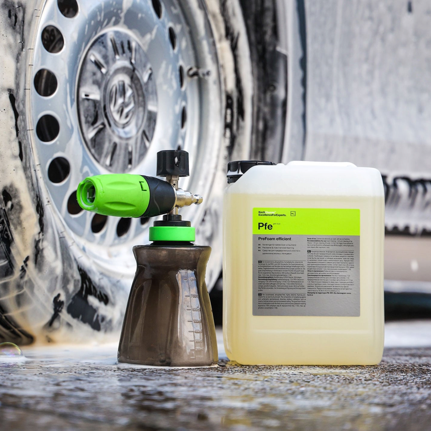 Koch-Chemie PreFoam Efficient alkaline pre-wash cleaner bottle and foam cannon used on a dirty car wheel.