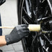 Person cleaning a car wheel with a sponge guru wheel brush