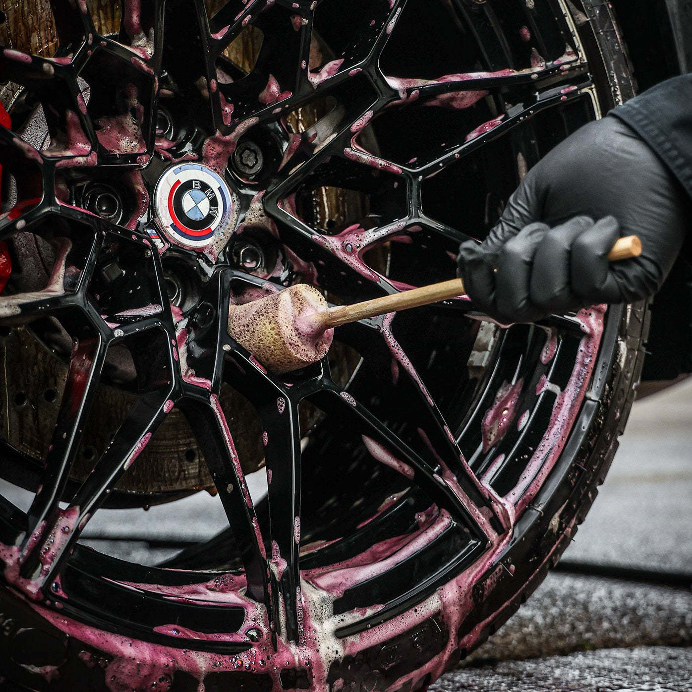 Person cleaning a BMW wheel with a sponge guru wheel brush