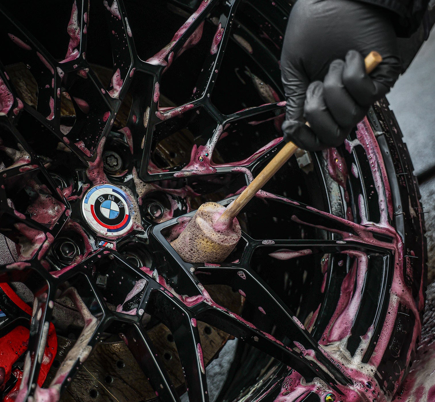 Person cleaning a BMW wheel with a brush