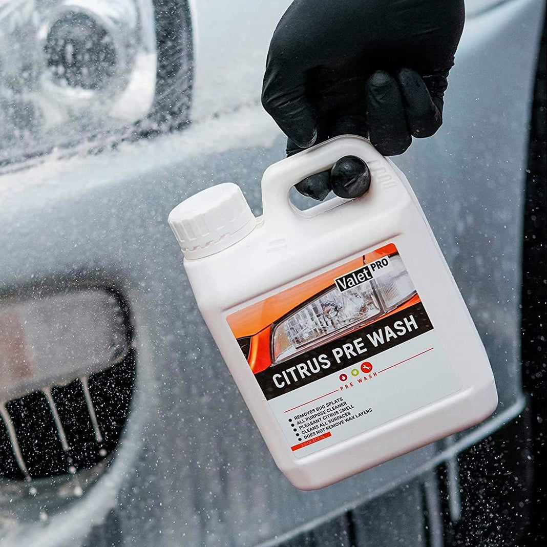 Hand holding a bottle of Valery Pro Citrus Pre Wash in front of a car windshield.